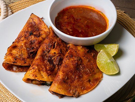 Quesabirrias - Crispy tortillas dipped in birria consommé, filled with tender slow-cooked birria meat